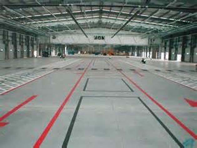 Red and grey lines marking out zones on the bare concrete floor of a large empty industrial building