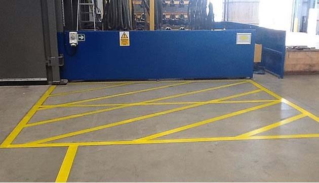 Yellow hatched keep-clear lines on a concrete floor in front of a blue loading door