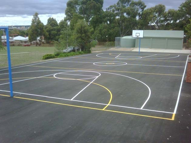A school court with white and yellow lines and a basketball hoop on a blue post