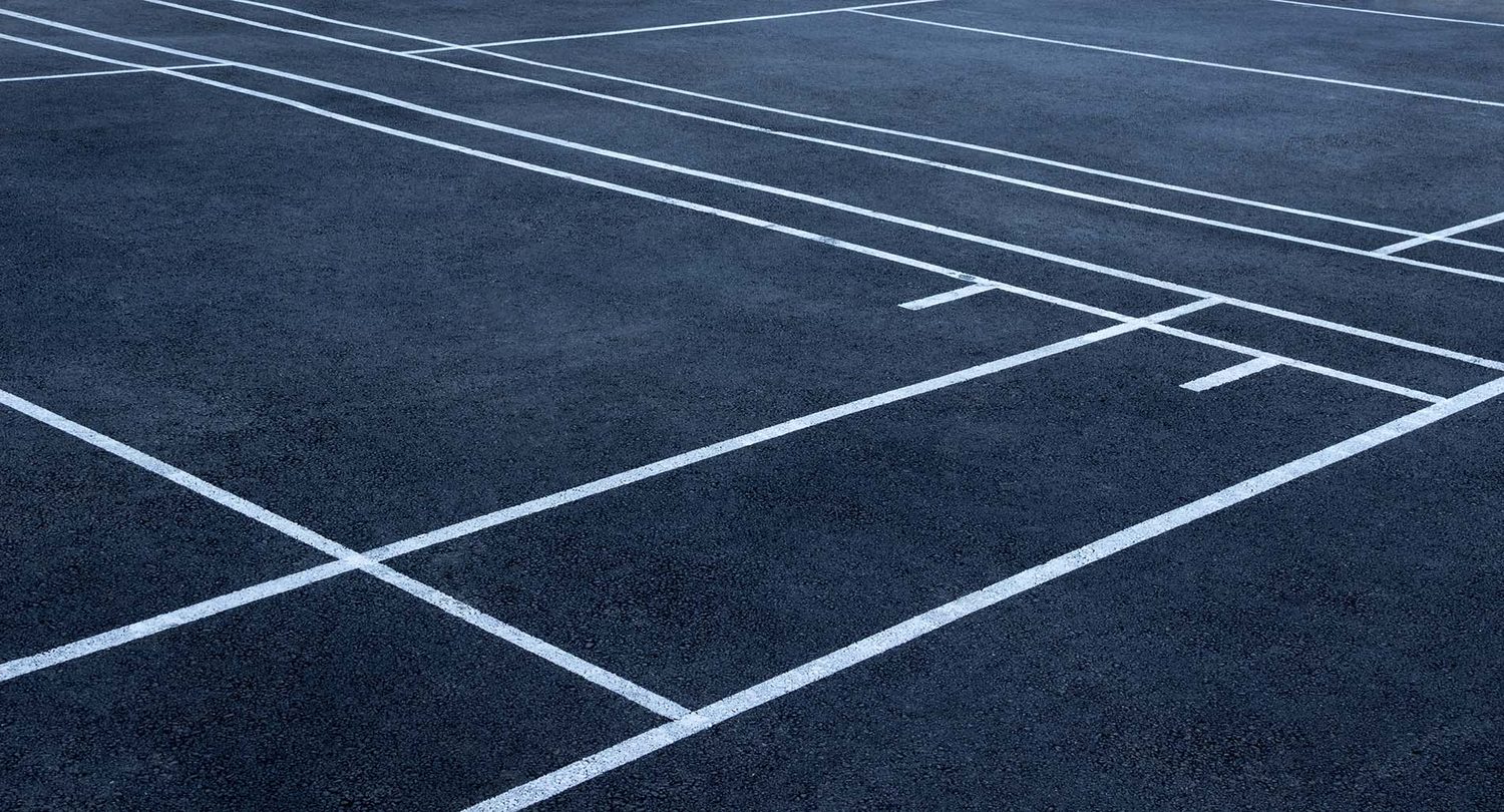 White court lines crossing a dark asphalt sports court, seen close up