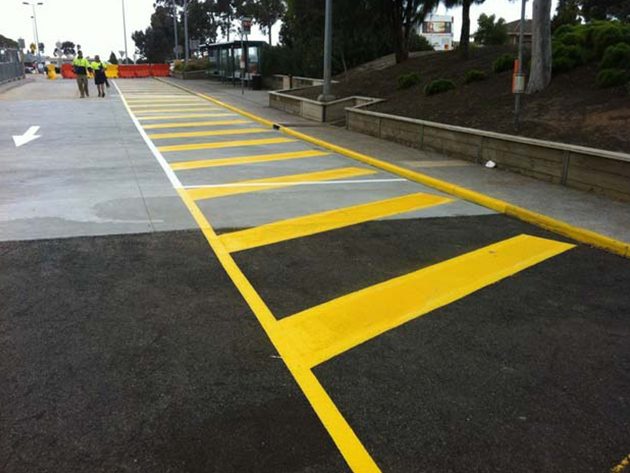 Yellow hatched pedestrian crossing bars painted across a car park entrance