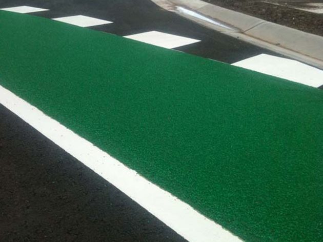 A green anti-skid cycle lane with a white edge line and white blocks along the kerb